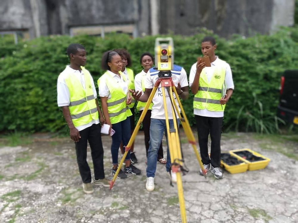 Étudiants réunis autour d'une station totale lors d'une sortie terrain de topographie.